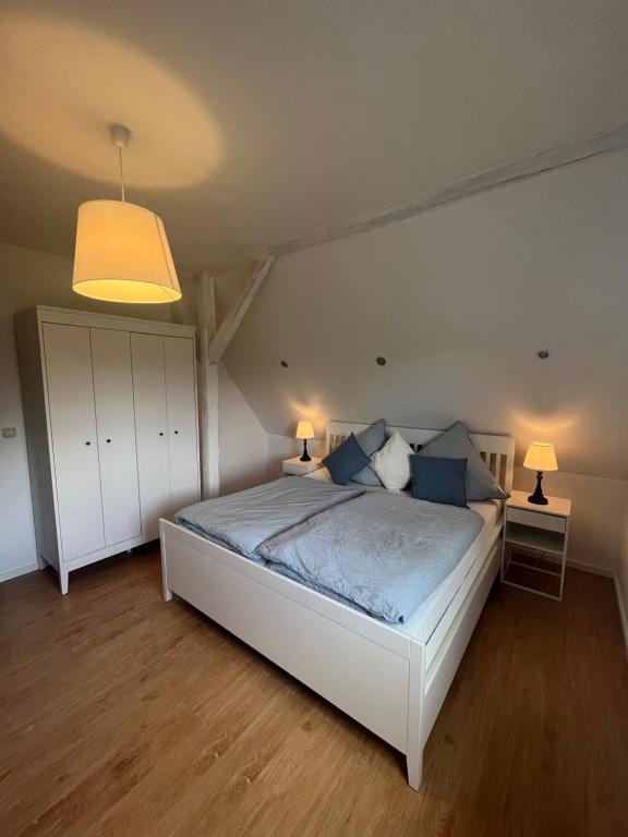 a bedroom with a large white bed with blue pillows at Ferienwohnung Mangold in Neuenkirchen