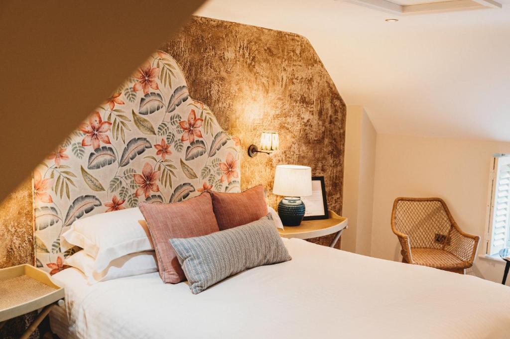 a bedroom with a white bed with a floral headboard at Finch's Arms in Oakham