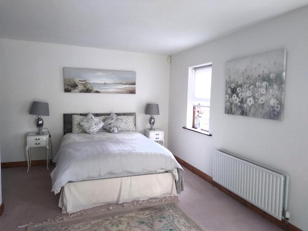a white bedroom with a bed and a window at Dunroven Guest House in Carlow