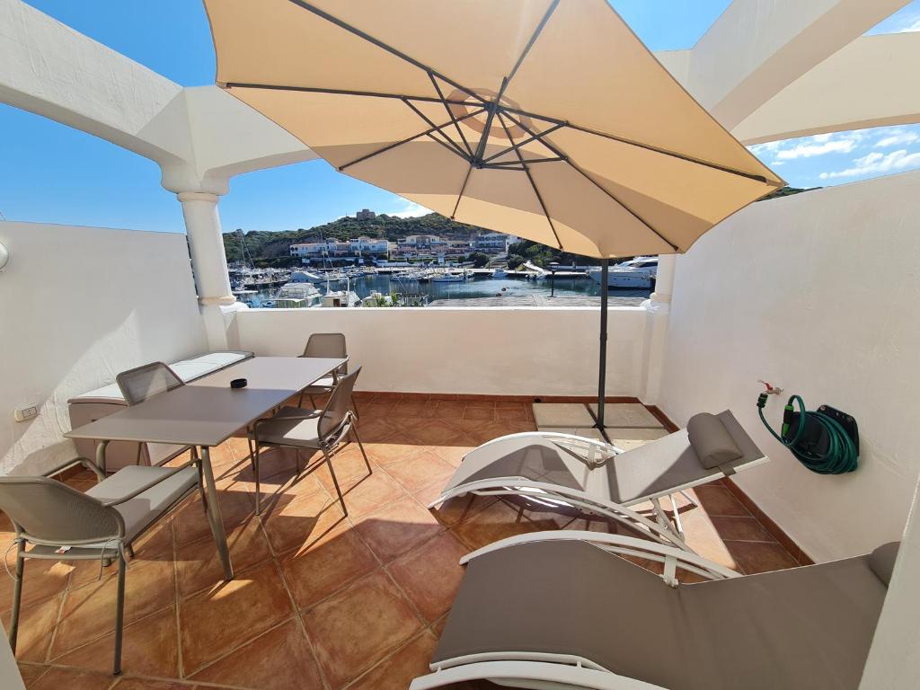 een balkon met een tafel en stoelen en een parasol bij La chicca del porto in Santa Teresa Gallura