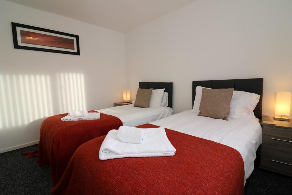 2 Betten in einem Hotelzimmer mit Handtüchern darauf in der Unterkunft Signature - Atholl House Glasgow Airport in Paisley
