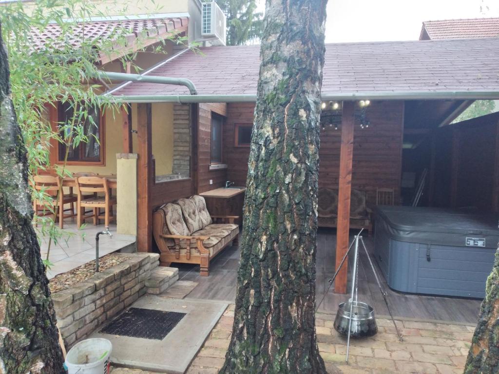 a house with a patio with a grill and a tree at Halász Vendégház Tiszakécske in Tiszakécske