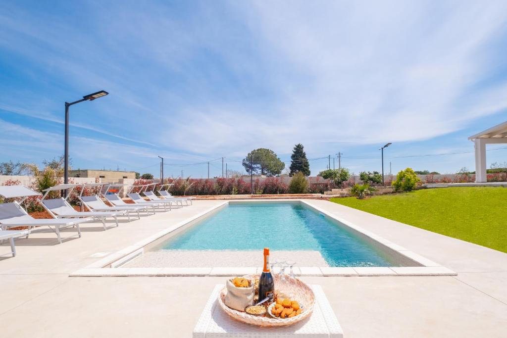 a swimming pool with chairs and a bowl of fruit next to it at Villa Palamita Luxury - Specchia in Specchia