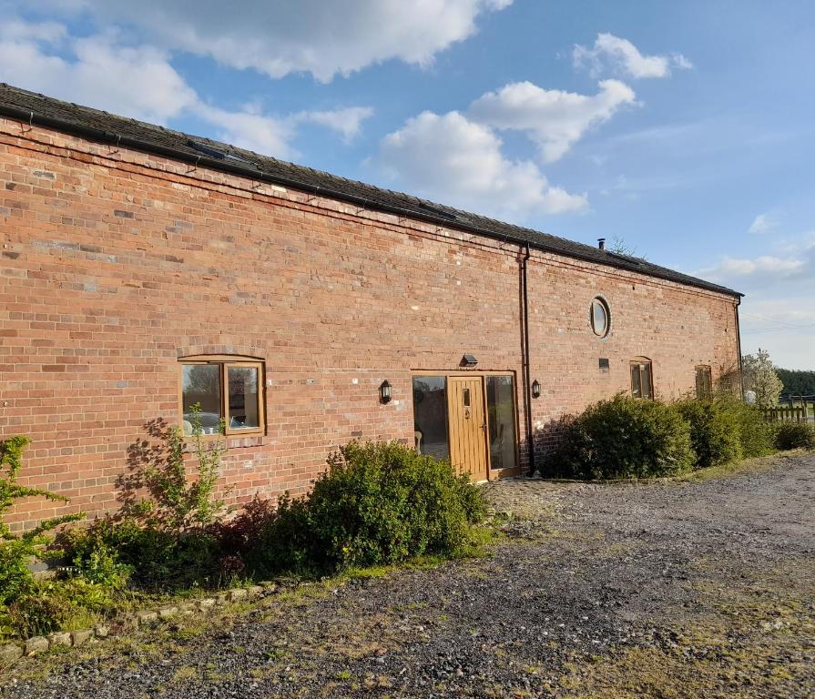 um velho edifício de tijolos com uma porta lateral em Mile House Barn Bed & Breakfast em Nantwich