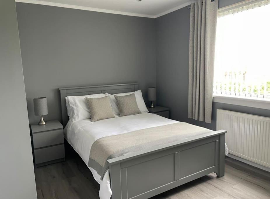 a bedroom with a bed with white sheets and a window at ESNA, Stromness in Stromness