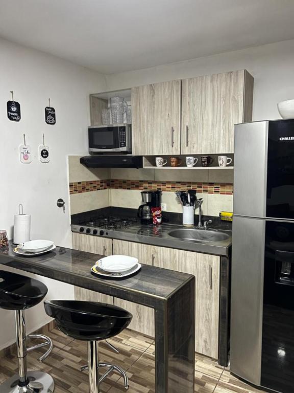 eine Küche mit Holzschränken und einem Kühlschrank aus Edelstahl in der Unterkunft Apartamento central en Itagui in Itagüí