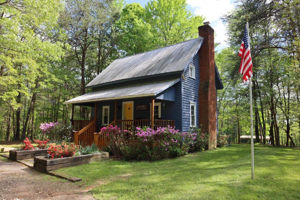 Landrum的住宿－Romantic, Secluded Historic Cottage on 5 Acres 30 mins to TIEC，院子中带旗帜的小蓝色房子
