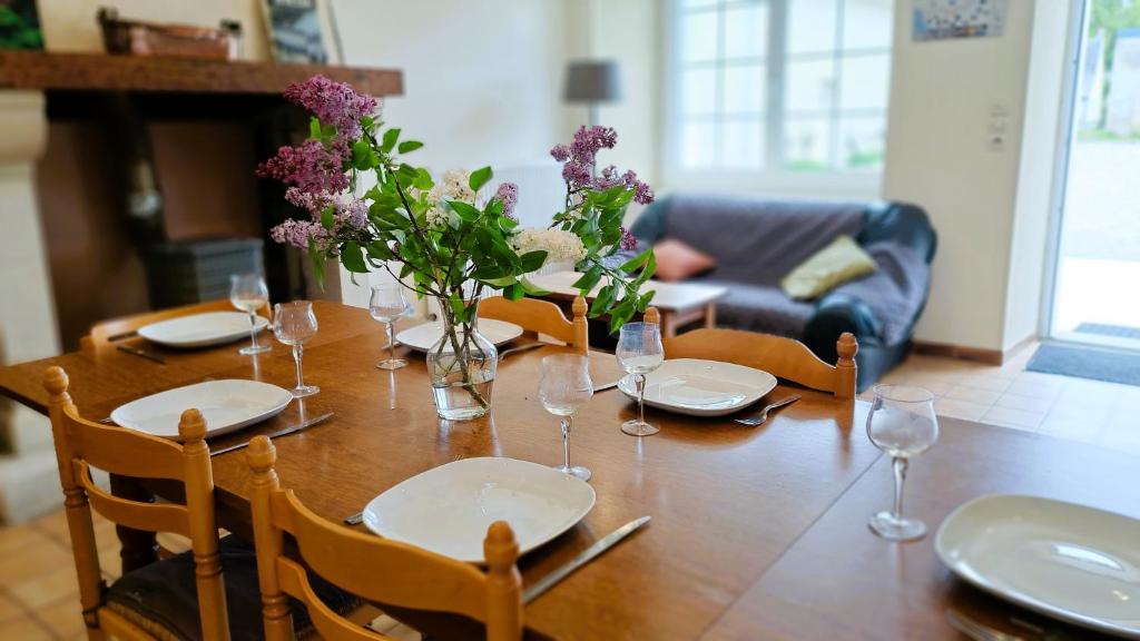 un tavolo in legno con piatti e bicchieri e fiori di Charme en Touraine 7p #châteaux #nature #vignobles 