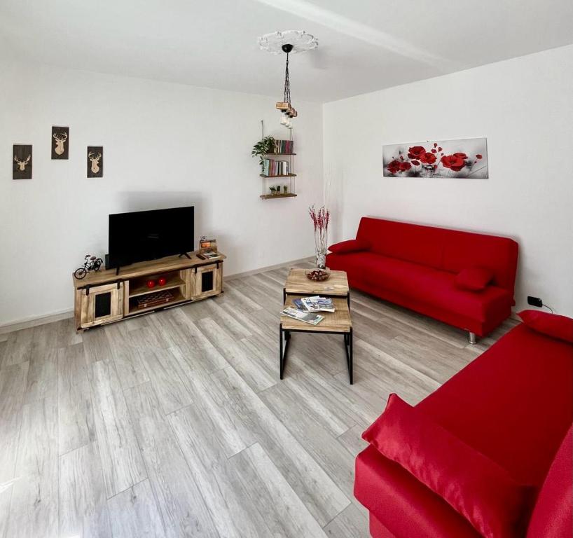 sala de estar con sofá rojo y TV en La Casa Di Sabi, en Locana