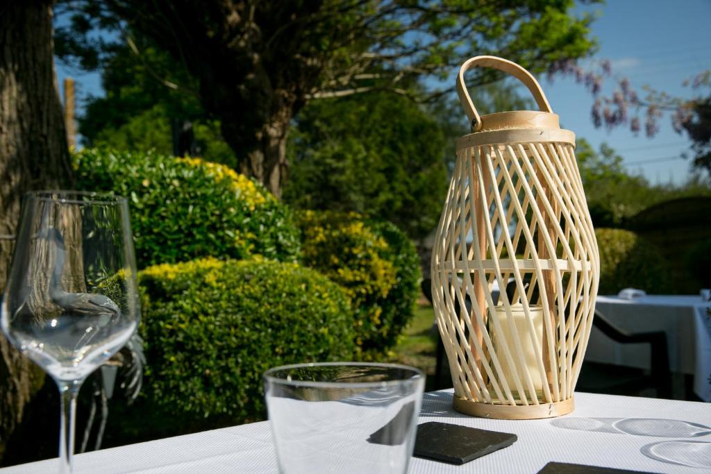 een tafel met een vaas en een glas water bij Logis Auberge De L'ombrée in Combrée