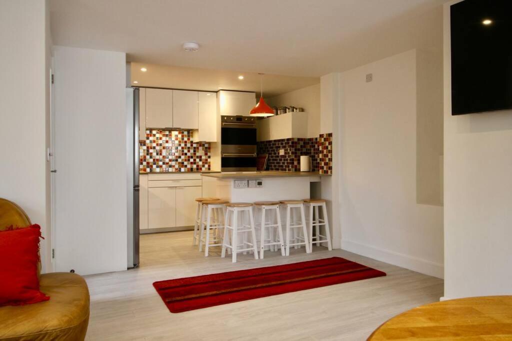 a living room with a kitchen with a red rug at Spacious comfortable & private parking in town centre in Cheltenham