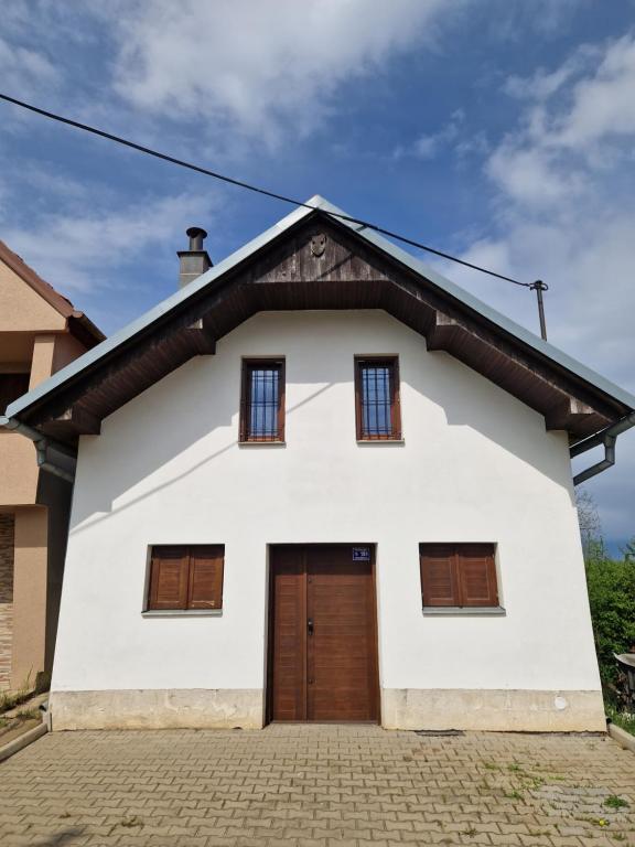 a white house with a brown door at Sklípek u kapličky in Velké Bílovice