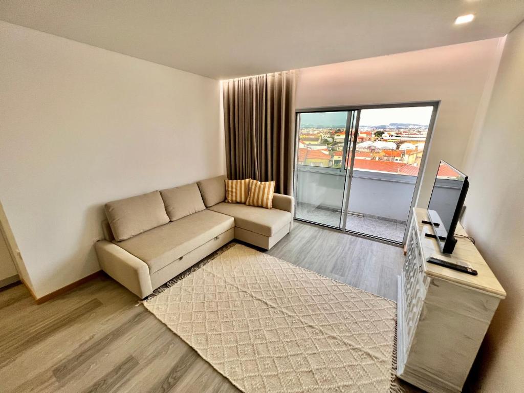 a living room with a couch and a television at Charming Studio Apartment in Povoa de Varzim in Póvoa de Varzim