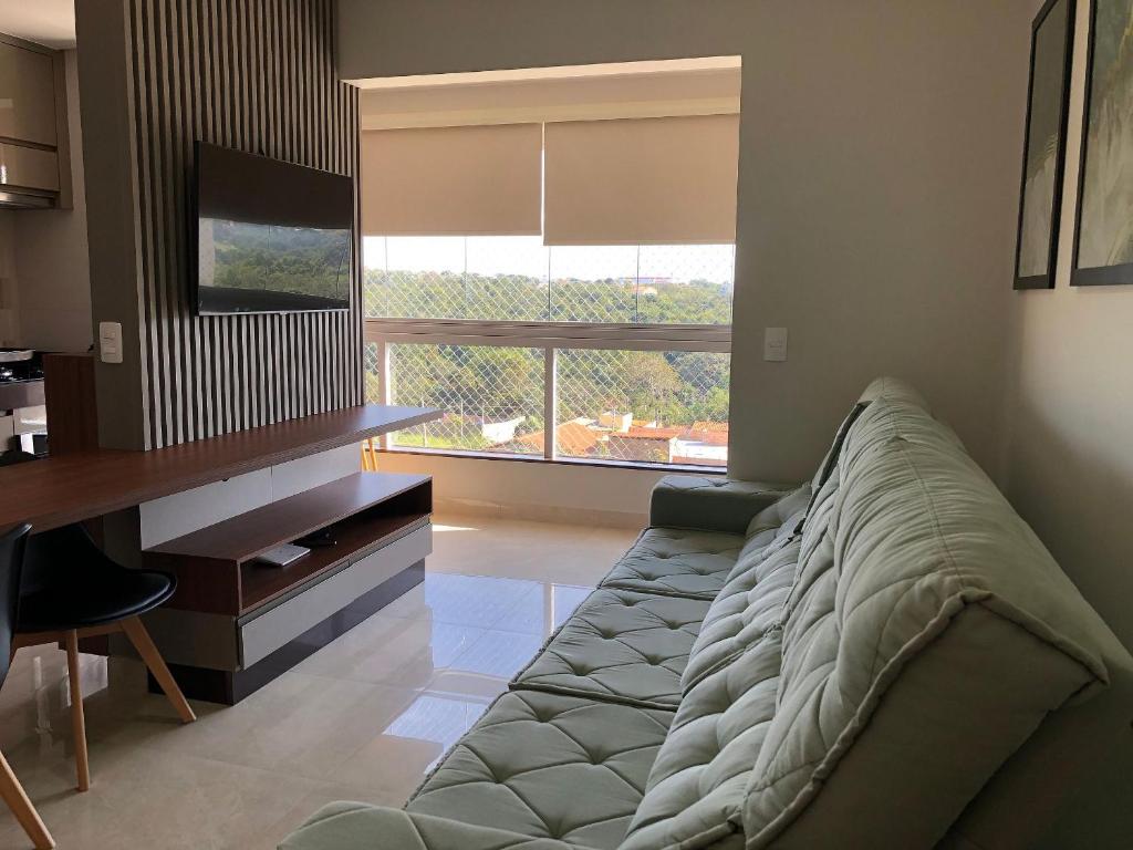 een woonkamer met een bank en een groot raam bij Condomínio Recanto do Bosque - RBF-01 in Caldas Novas