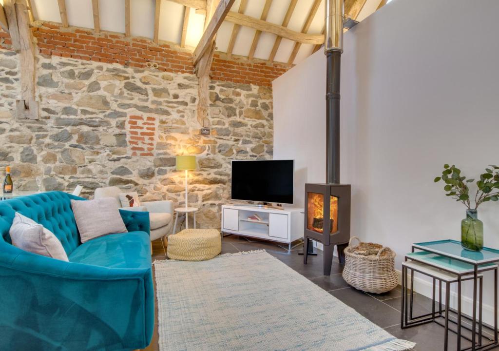 a living room with a blue couch and a fireplace at Bedwen in Llanfihangel-geneuʼr-glyn