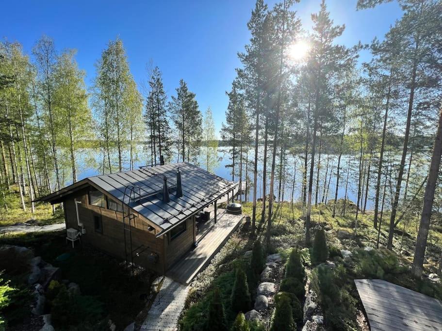 a cabin in the woods next to a body of water at Luxury guesthouse, beachfront sauna in Jyväskylä