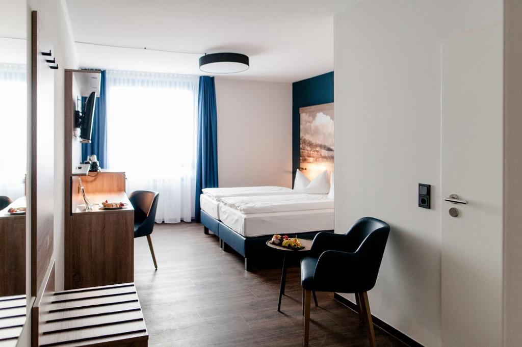 ライプツィヒにあるAtlanta Hotel Leipzigのベッド、テーブル、椅子が備わるホテルルームです。