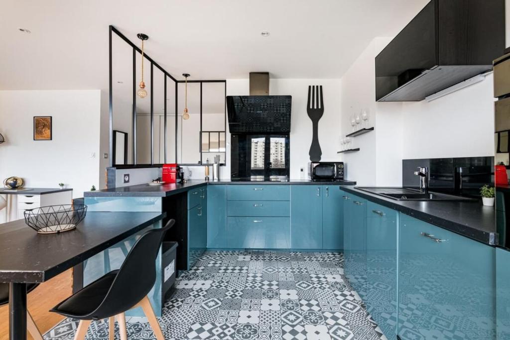 uma grande cozinha com armários azuis e uma mesa em Le Grand Fauriel 100m 6 places em Saint-Étienne