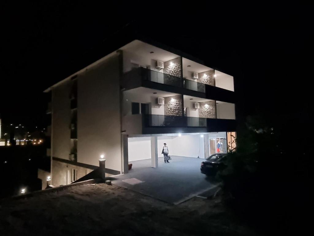 uma pessoa andando em frente a um edifício à noite em Apartman Casa em Trebinje
