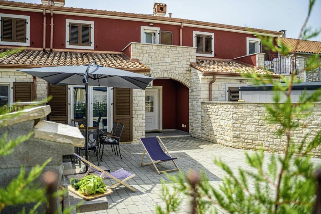a patio with chairs and an umbrella in front of a house at Casa Maja in Brtonigla