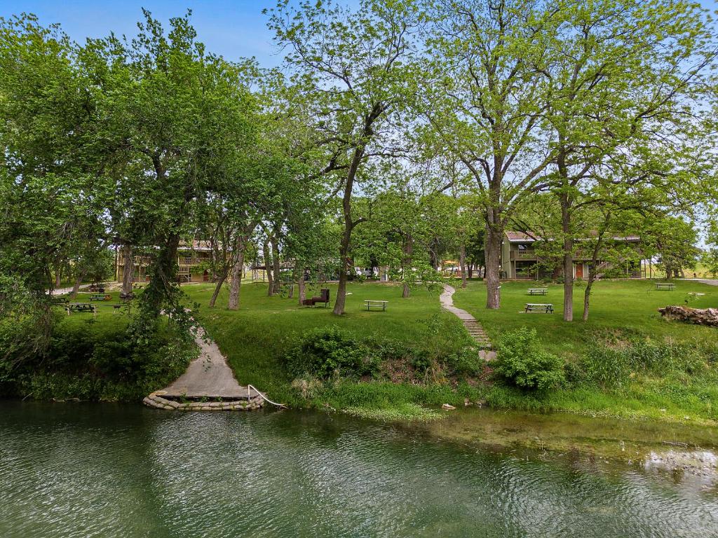 a river in a park with trees and a field at Gruene Outpost River Lodge in New Braunfels