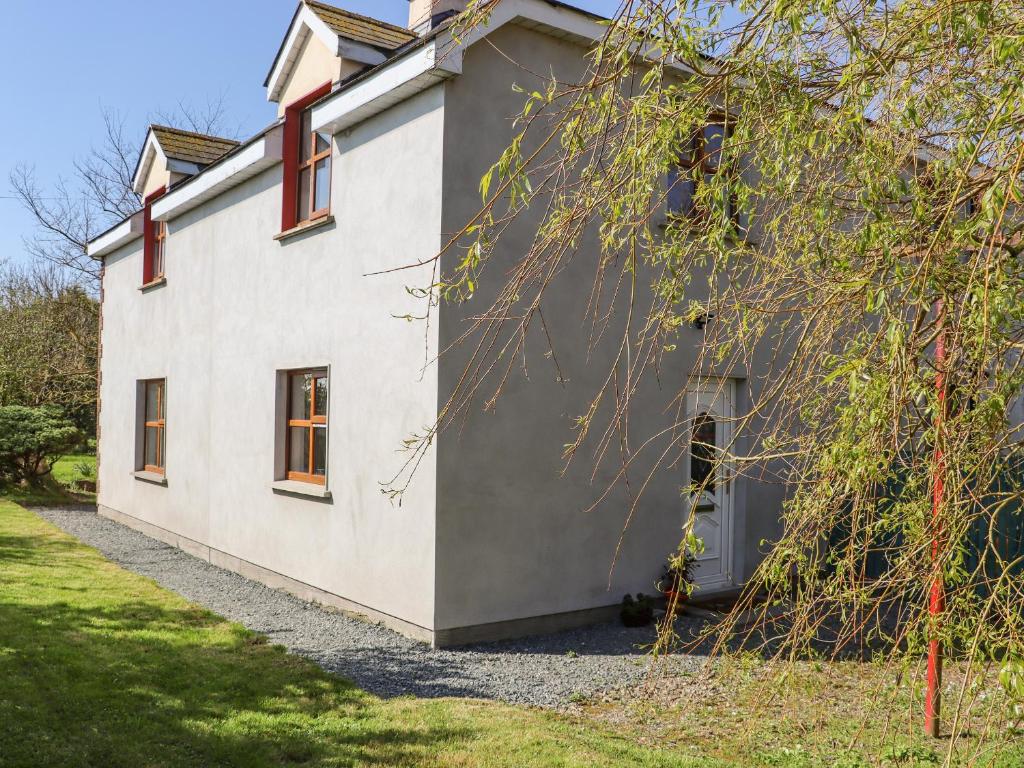 a white house with red windows on the side of it at Wheatfield Lodge in Fethard on Sea