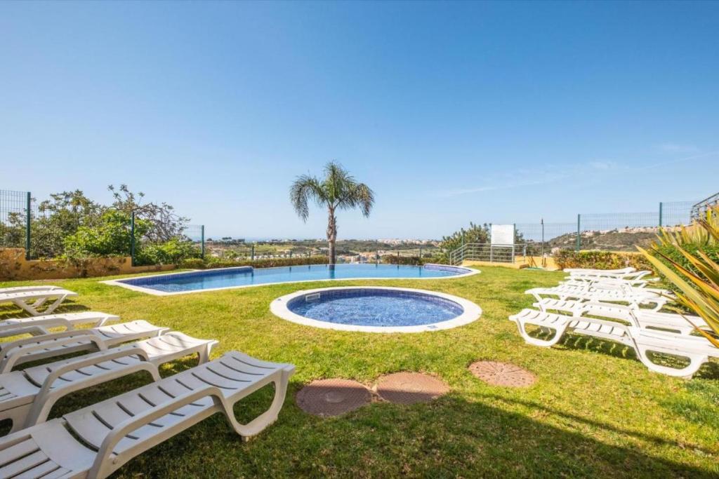 a group of white lounge chairs and a pool at Flat with Pool Marina and Sea View in Albufeira