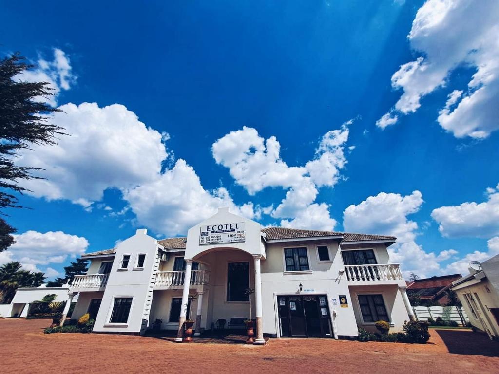 uma casa branca com um céu azul e nuvens em Ecotel OR Tambo Airport em Kempton Park