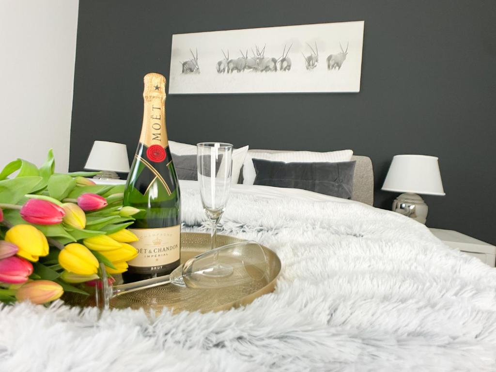 a bottle of champagne and a bouquet of flowers on a bed at M-Style 01 Apartment mit Terrasse und Gasgrill, 24h Self-Check-In, Free Parking, Netflix in Nürnberg