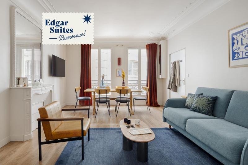 a living room with a blue couch and a table at Edgar Suites Grands Boulevards - Boulanger in Paris