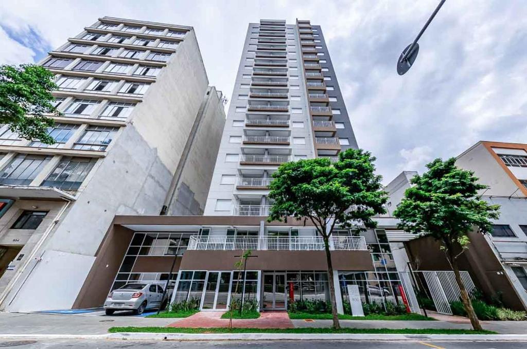 Un edificio alto y blanco con árboles delante. en Studio 27m2 Wifi Liberdade Proximo Metro Restaurante Hospital, en São Paulo