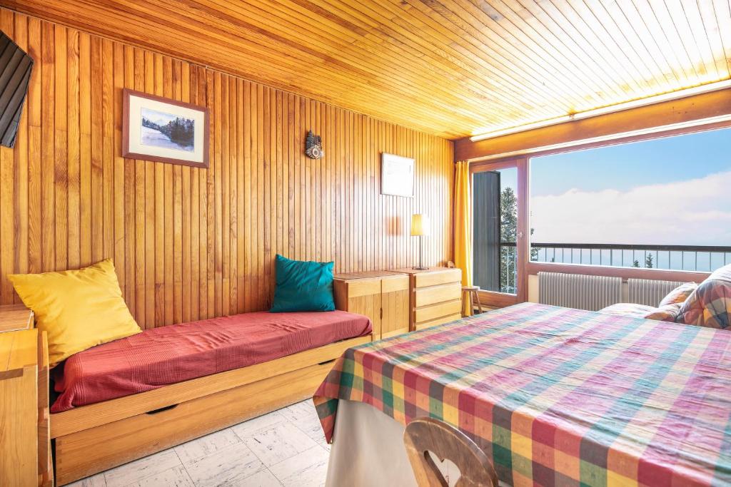 une chambre avec deux lits et une grande fenêtre dans l'établissement L'Arcelle - à 50 mètres des télésièges, à Chamrousse