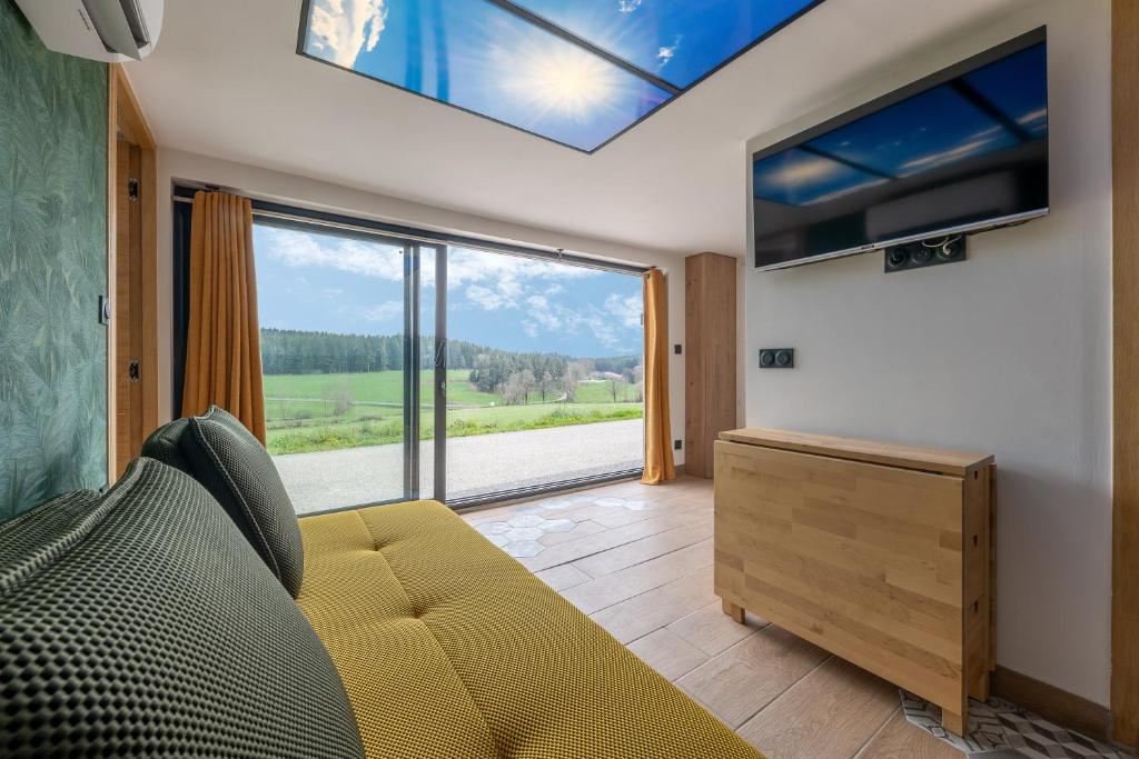 a living room with a couch and a large window at Prunières - Joli T2 dans la Haute-Loire in Saint-Pal-de-Mons