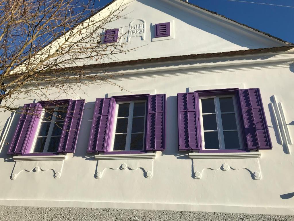 a white house with purple shuttered windows at Der Reinerhof in Kroatisch Reinersdorf
