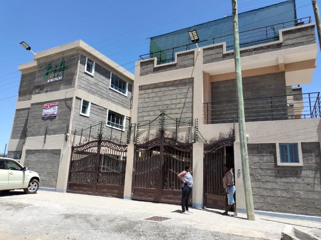 dos personas de pie en frente de un edificio con una puerta en Executive 1&2 Broom Airbnb in Gilgil Nakuru, en Gilgil