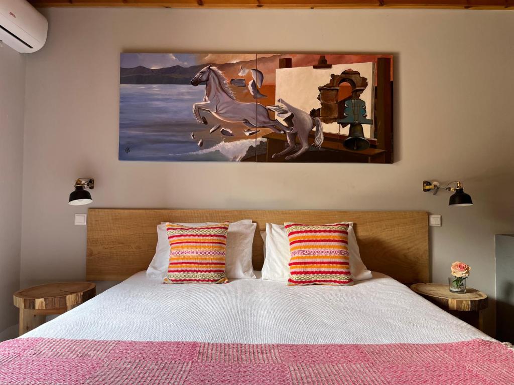 a bedroom with a bed with a painting on the wall at Pico Formoso Vínea Lava Alojamentos Pico in Prainha de Baixo