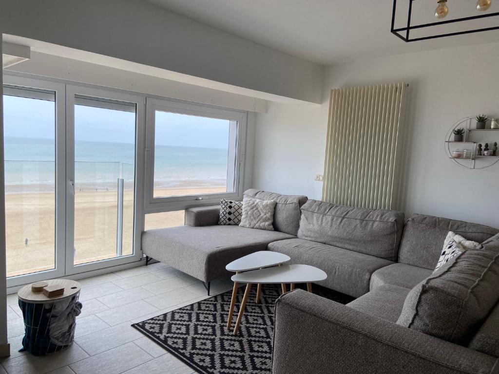 a living room with a couch and a view of the beach at Appartement vue sur mer - Splendide localisation! in Sint-Idesbald