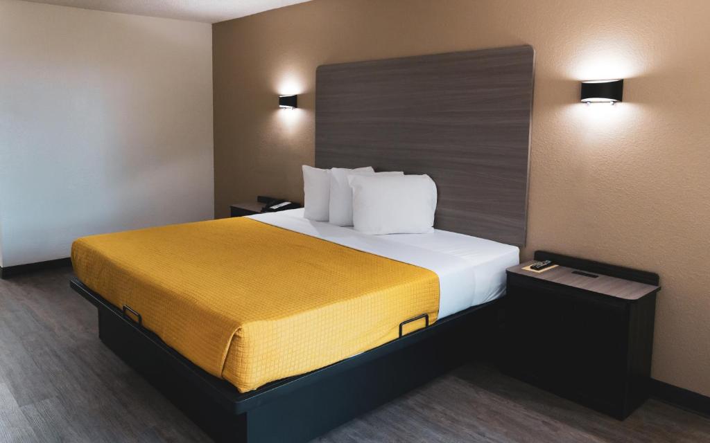 a hotel room with a bed with a yellow blanket at Express Inn & Suites in Palestine