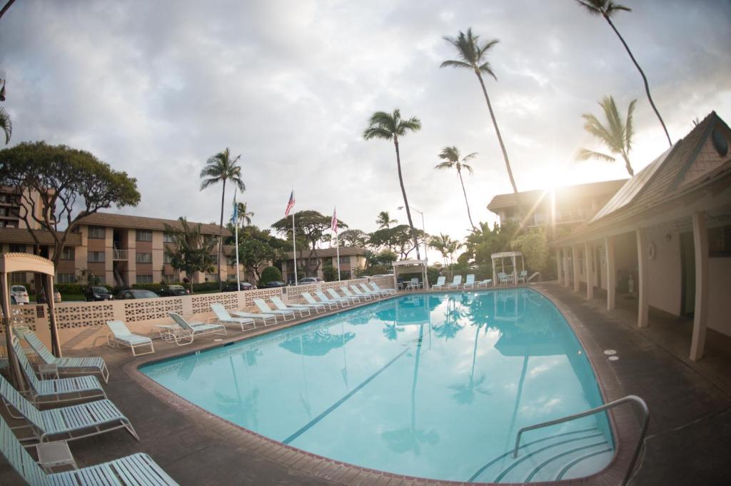 una piscina en un hotel con sillas y palmeras en Kihei Kai Nani - Maui Vista, en Wailea