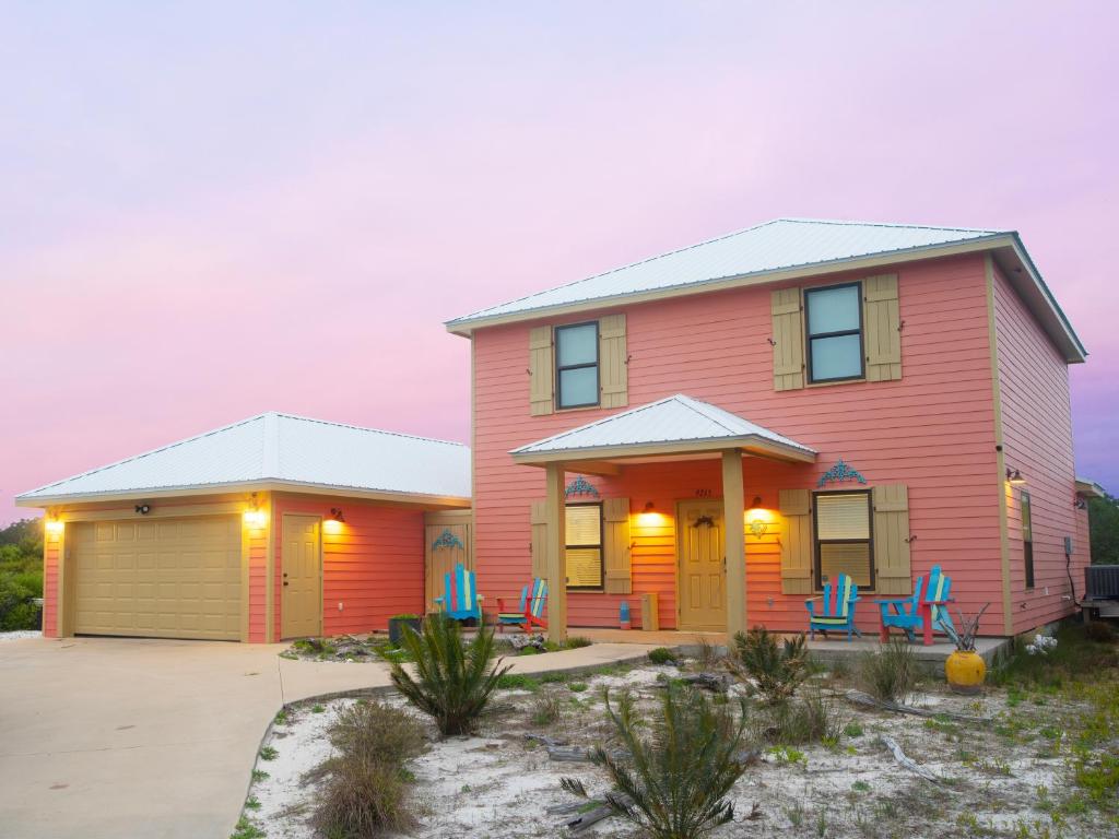 una casa roja con sillas azules delante de ella en Walk to Beach, Secluded, Gazebo with Grill, 1GiG WiFi, Washer and Dryer, Games, en Gulf Shores