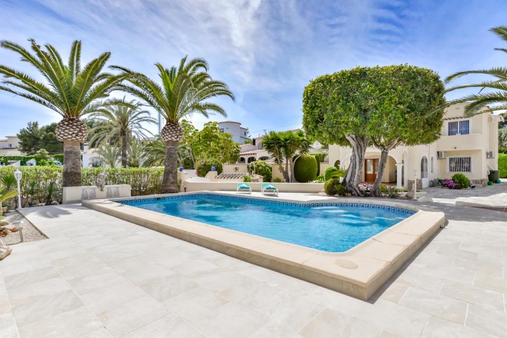 a swimming pool in a yard with palm trees at Villas Guzman - Altamira in Benissa