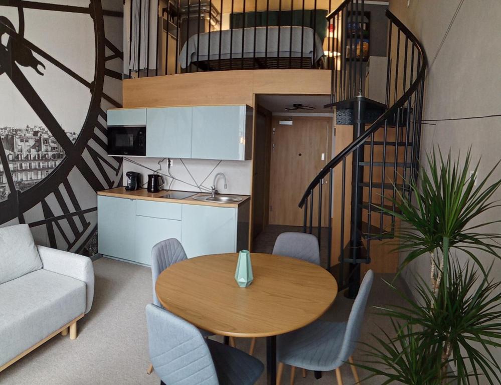 ein Wohnzimmer mit einem Tisch, Stühlen und einer Treppe in der Unterkunft Wroclove Airport Loft in Breslau