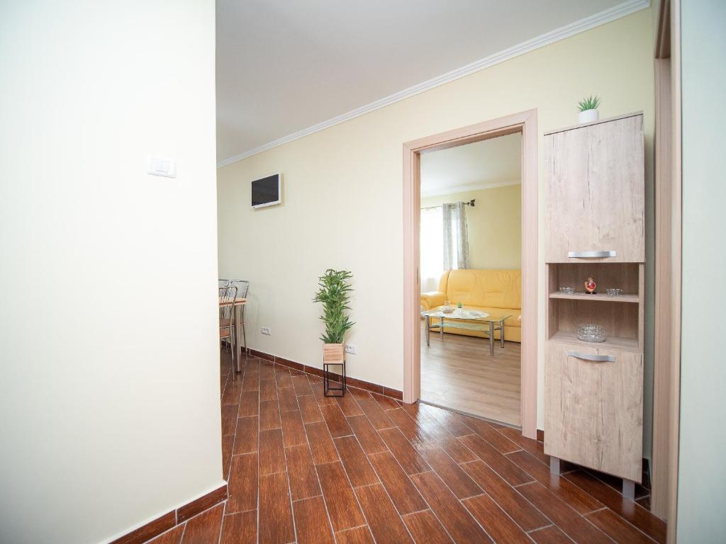 a living room with a wooden floor and a hallway at L&R Modern Apartment in Oţelu Roşu
