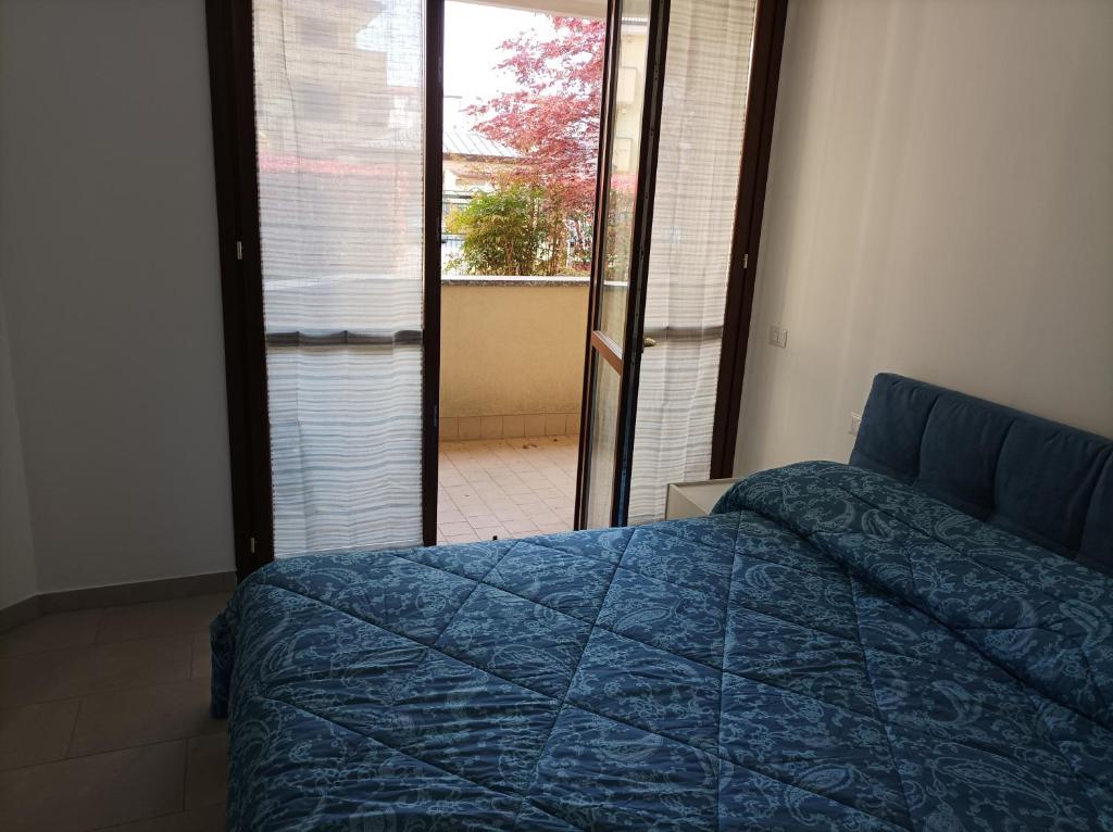 - une chambre avec un lit bleu et une porte donnant sur une terrasse dans l'établissement Camera doppia privata vicino Milano con bagno in comune, à Concorezzo
