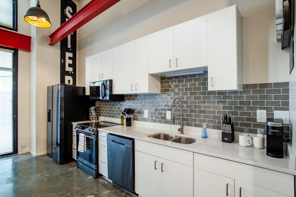 a kitchen with white cabinets and a black refrigerator at Historic Downtown Loft with Modern Flare in Knoxville