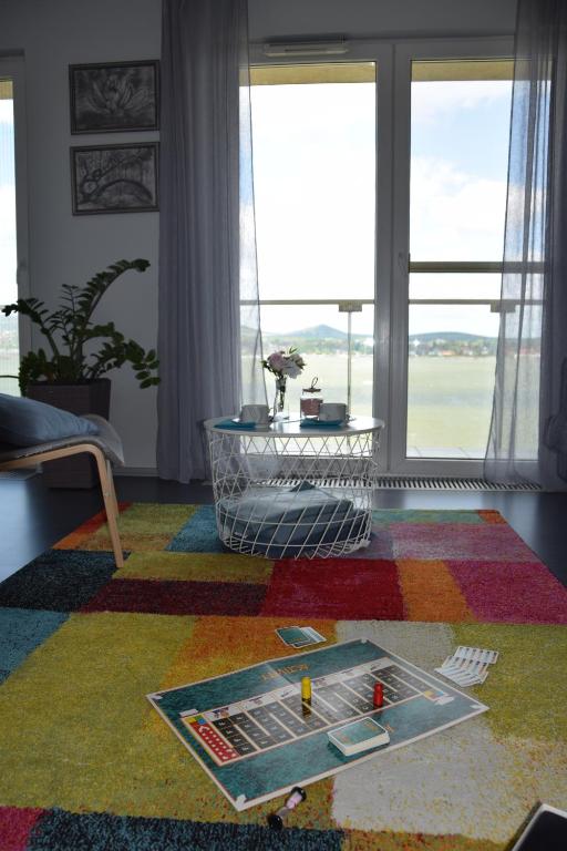 a living room with a colorful rug and windows at Panorama Apartman in Velence