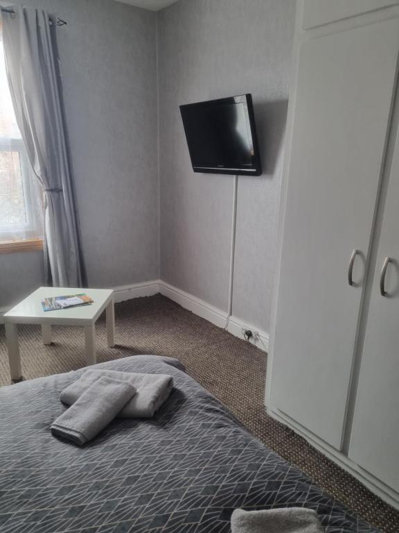 a bedroom with a bed with a flat screen tv on the wall at Leeds House Guest House in Bridlington