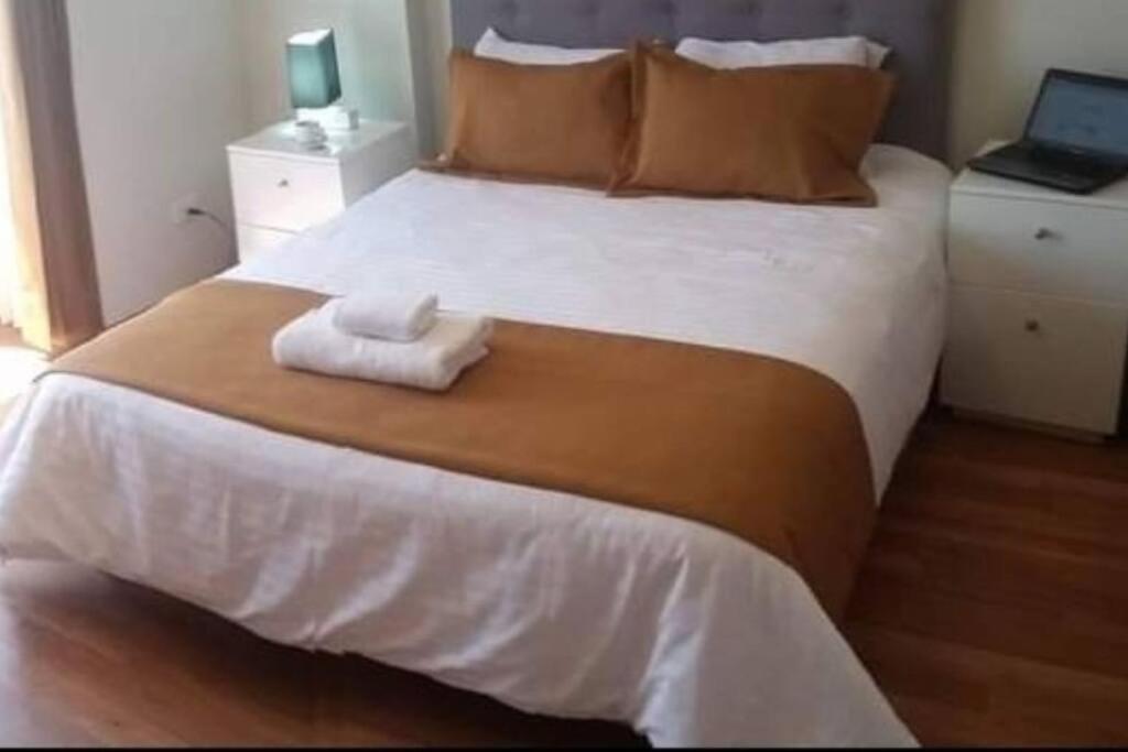 a bedroom with a large white bed with a towel on it at ApartHotel moderno y céntrico por la Av. Dolores in La Pampilla
