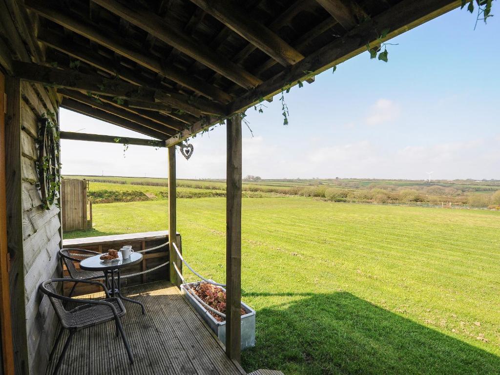 a porch with a table and chairs and a field at The Cabin in Bude