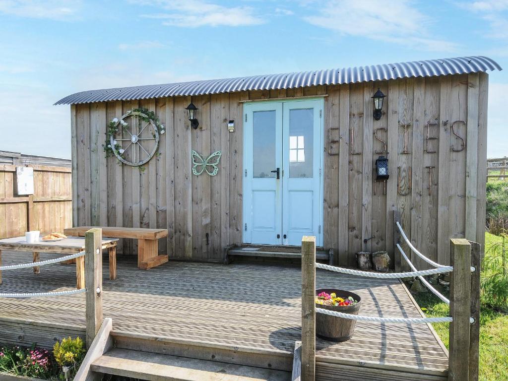 a wooden shed with a blue door on a deck at Elsie's Hut in Bude